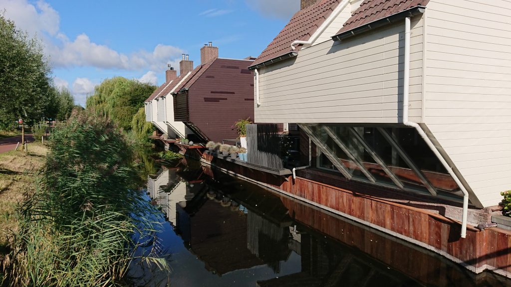 houtskeletbouw woningen met schuine glazen gevel boven het water